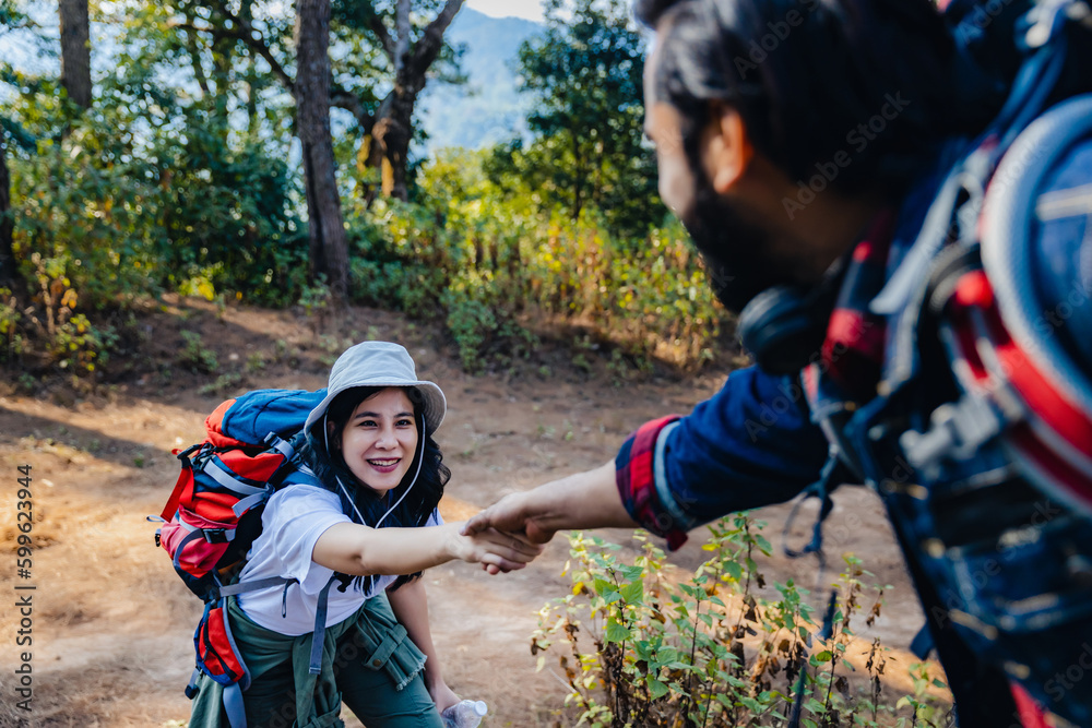 Woman hike being pulled up by helping hand. Hiker friends help each other up a mountain. Man and woman giving a helping hand and active fit lifestyle. Hikers with backpacks helping friend to climb Woman hike being pulled up by helping hand. Hiker friends help each other up a mountain. Man and woman giving a helping hand and active fit lifestyle. Hikers with backpacks helping friend to climb
