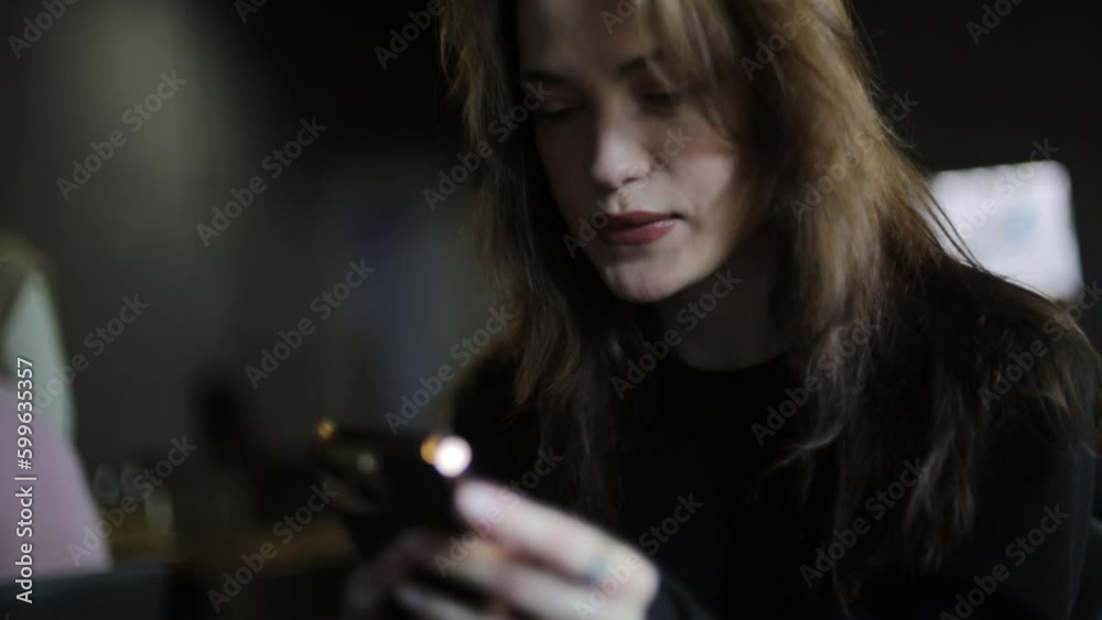 beautiful woman is typing a message in a smartphone in a cafe.