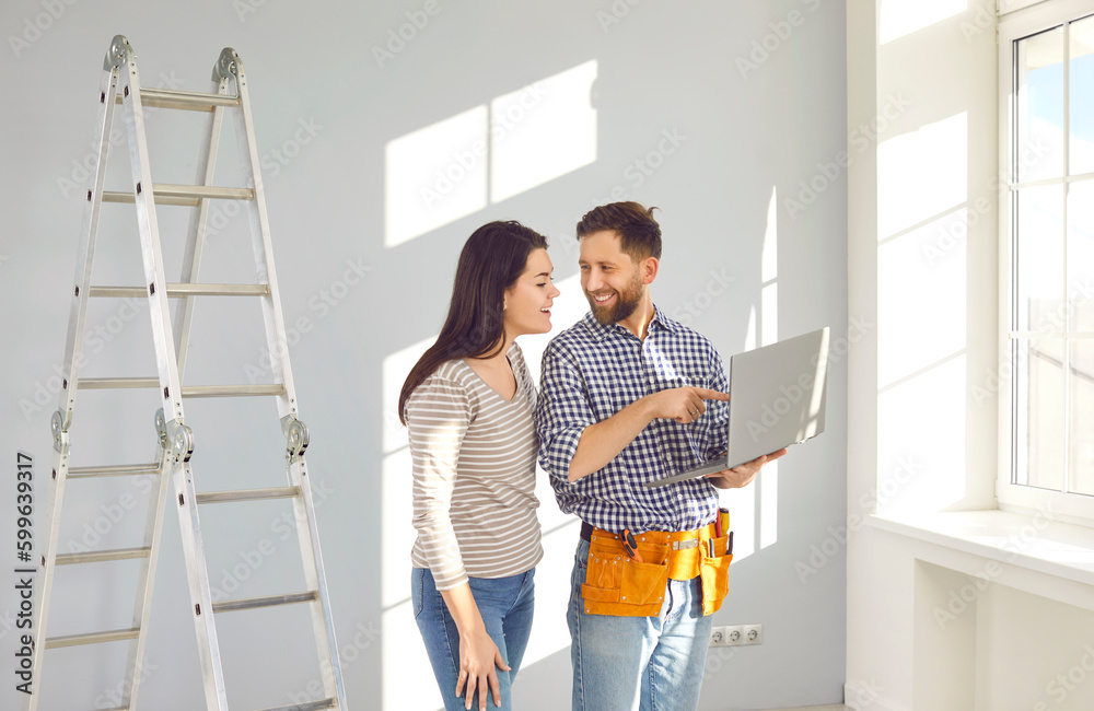 © Studio Romantic - Repairman with laptop talking to young woman. Worker with tool belt standing in room with step ladder, holding modern laptop computer and discussing repairs inside the house with young woman homeowner