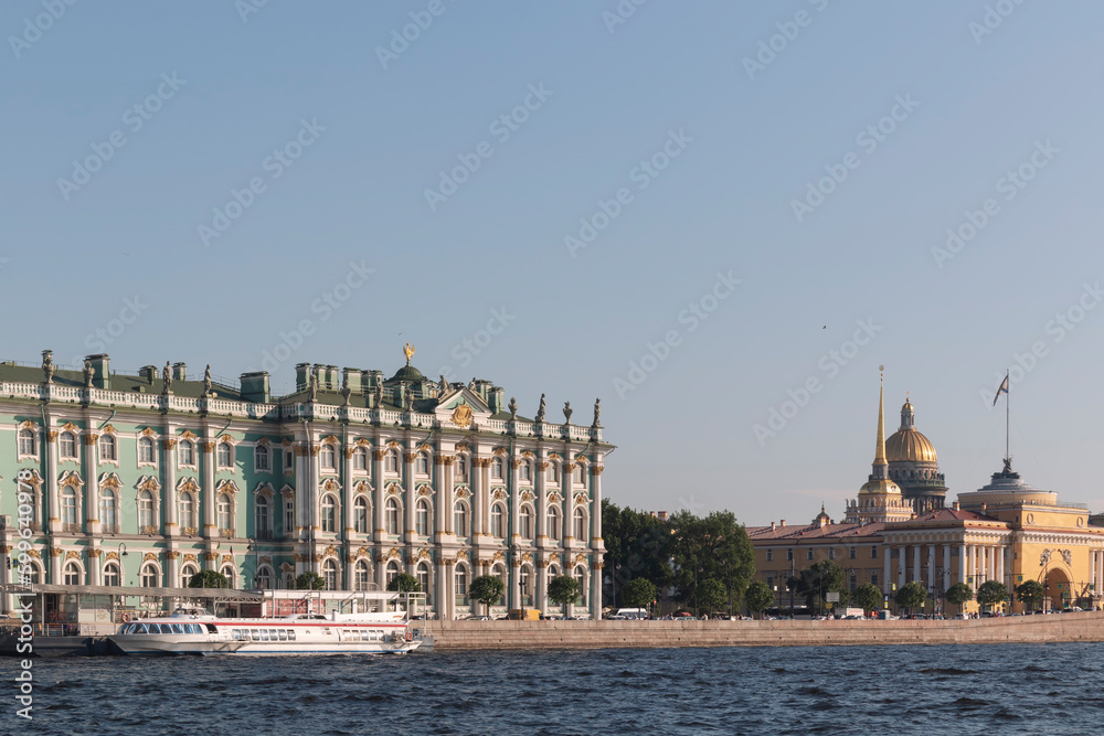 A view from a river on Hermitage and Saint Isaac's Cathedral by a warm summer day. Landmarks of Saint Petersburg. A speed boat and an embankment in front.
