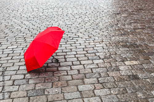Wet red umbrella on a wet stone pavement.