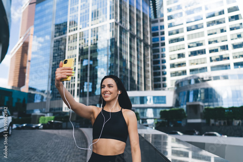 Happy sportswoman taking selfie with cellphone on street