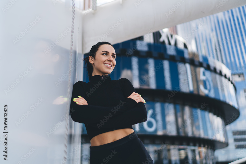 Fototapeta premium Cheerful woman in sportswear admiring view of city