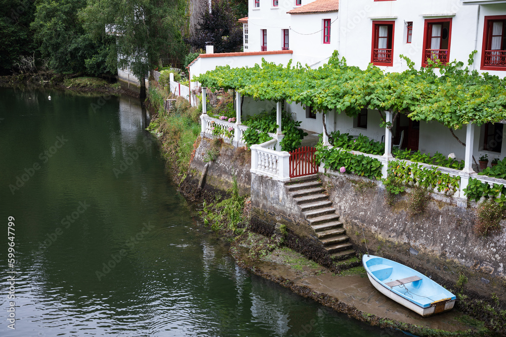 Una bella casa con embarcadero a orillas de un río con una terraza y su parra en Galicia, España.
