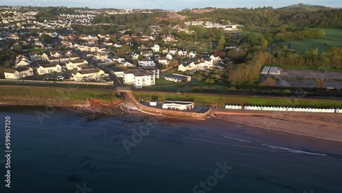 Goodrington Sands, Torbay, South Devon, England: DRONE AERIAL VIEWS: The drone zooms out from Goodrington Sands promenade to show South Sands cafe, the beach and sea, a row of colourful beach huts. photo