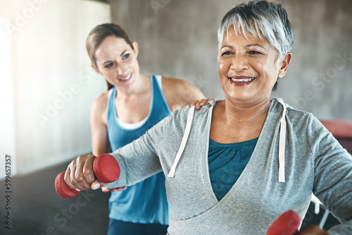 Physical therapy, dumbbell and fitness with old woman and personal trainer for support, health and physiotherapy. Training, weightlifting and coaching with senior patient and female trainer for help