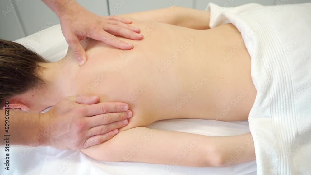 Woman on therapeutic spine massage in clinic lying on couch, top view. Medical massage for healing. Massagist, therapist treats patient lying on a couch. Treatment, cure, procedure. Woman on therapeutic spine massage in clinic lying on couch, top view. Medical massage for healing. Massagist, therapist treats patient lying on a couch. Treatment, cure, procedure.