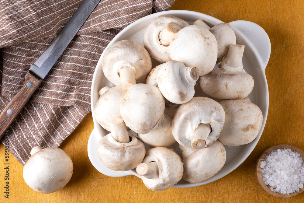 Close-up of champignon mushrooms on a white ceramic plate on a yellow background. Selective focus. Close-up of champignon mushrooms on a white ceramic plate on a yellow background. Selective focus.