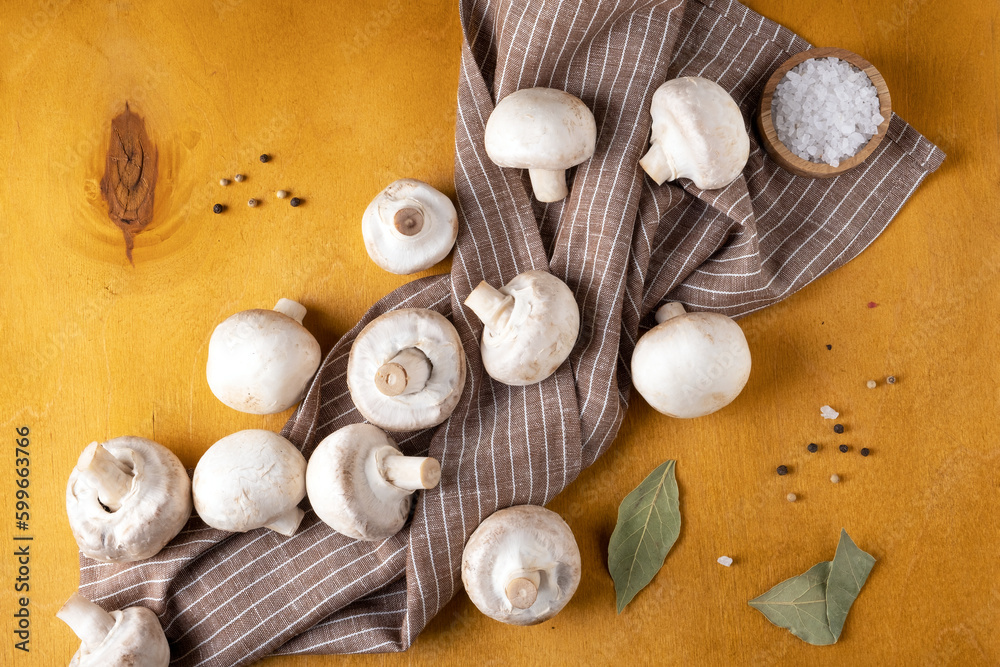 Close-up of champignon mushrooms on a linen napkin on a yellow background. Selective focus. Close-up of champignon mushrooms on a linen napkin on a yellow background. Selective focus.