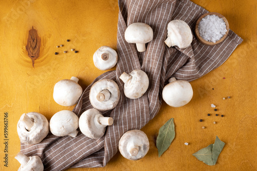 Close-up of champignon mushrooms on a linen napkin on a yellow background. Selective focus.