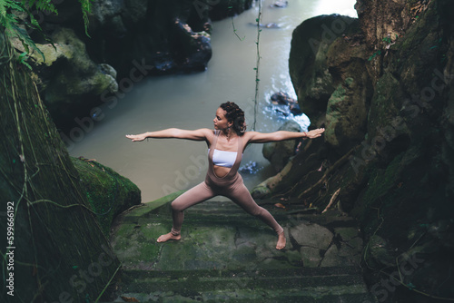 Calm female in sportive wear meditate in yoga pose during morning mindfulness concentration near cavernous river  Caucasian woman enjoying hatha practice for enlightenment harmony abundance