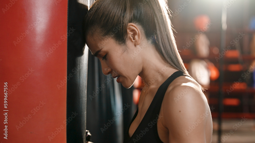 Asian female boxer boxing with sandbags in anger and tired His face showed despair. After being defeated by boxing with an opponent on the boxing ring. frustrated sad woman