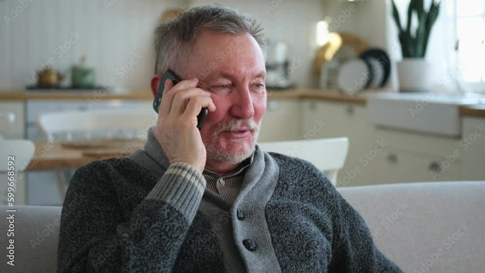 Happy middle aged senior man talking on smartphone with family friends. Older mature grandfather with cell phone talking with grown up children, resting at home. Older generation modern tech usage Happy middle aged senior man talking on smartphone with family friends. Older mature grandfather with cell phone talking with grown up children, resting at home. Older generation modern tech usage