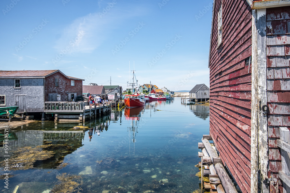 Naklejka premium Red boat docked in the bay of a fishing village at Peggy's Cove, Nova Scotia.