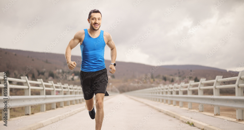 Fit man in sportswear running across a bridge