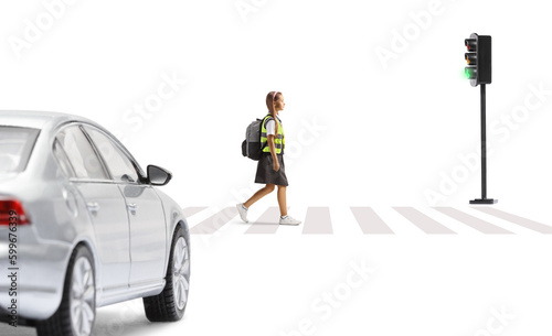 Car waiting and a schoolgirl with a safety vest crossing street at pedestrian crosswalk