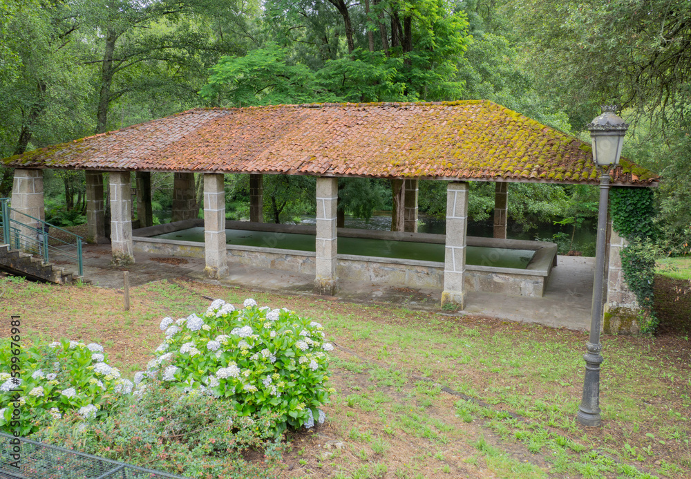 Old laundry room with tiled roof and columns, under water to wash clothes, surrounded by green nature in Ribadavia village in Orense, Galicia, summer 2021 Spain Old laundry room with tiled roof and columns, under water to wash clothes, surrounded by green nature in Ribadavia village in Orense, Galicia, summer 2021 Spain
