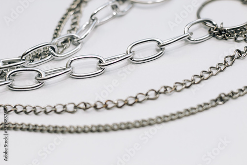 Different silver metal chains on a light background.
