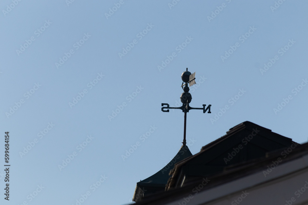 This weather vane was beautiful on the roof contrasted against the sky. The shadowy image with the clear blue sky in the background. The North, South, East, and West showing direction of the wind. This weather vane was beautiful on the roof contrasted against the sky. The shadowy image with the clear blue sky in the background. The North, South, East, and West showing direction of the wind.
