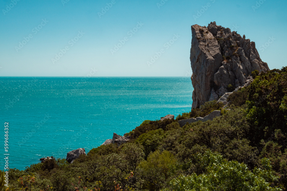 A high sheer cliff, beautiful blue sea and sky.