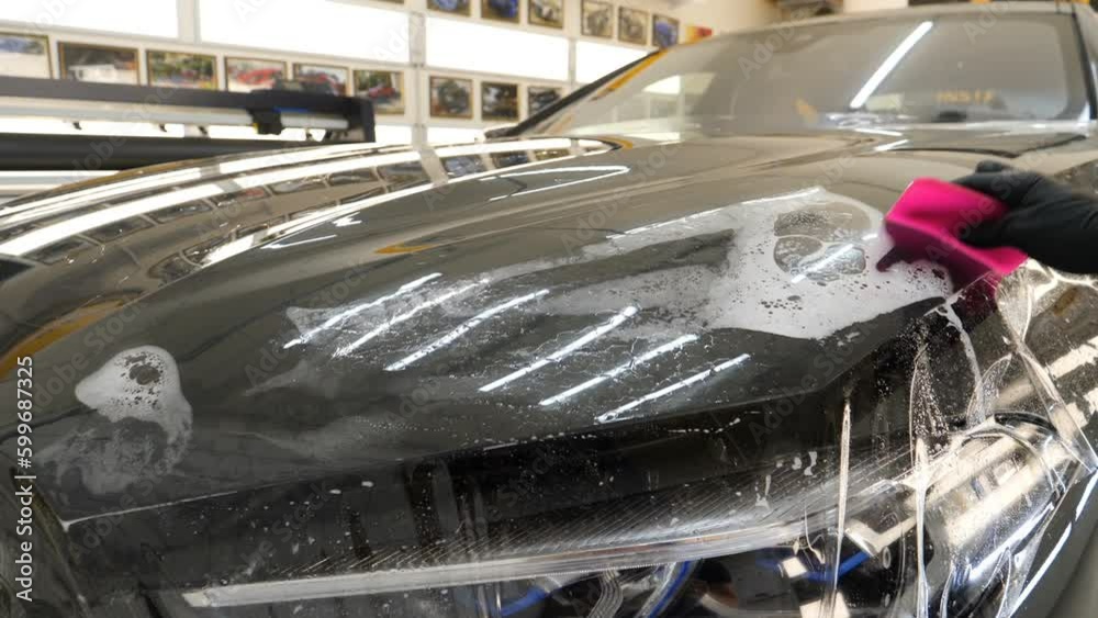 Close up to PPF installation process on a front headlight and hood. PPF
