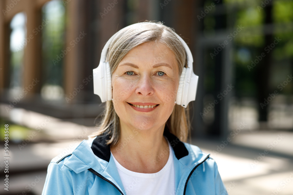 Smiled Mature Woman Looking at the Camera While Listen to Music Using Headphones. Sport and Healthy Lifestyle Concept Smiled Mature Woman Looking at the Camera While Listen to Music Using Headphones. Sport and Healthy Lifestyle Concept
