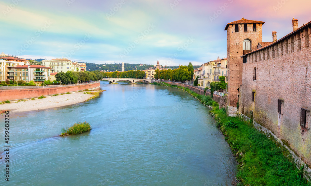 Panoramic view from the Ponte Pietra bridge in Verona on the Adige river in the morning, Veneto region. Dramatic sky with clouds. Ancient european italian terracotta color houses.