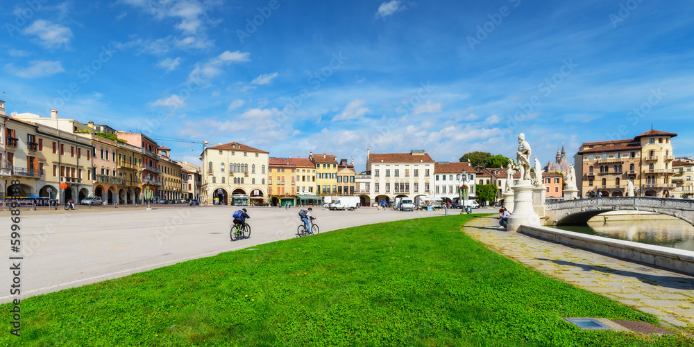 Cyclists in the square Prato della Valle in Padova (Padua), Veneto region, Italy. Cycling tourism. Sunny day, beautiful sky, soft light. Travel destination concept Cyclists in the square Prato della Valle in Padova (Padua), Veneto region, Italy. Cycling tourism. Sunny day, beautiful sky, soft light. Travel destination concept