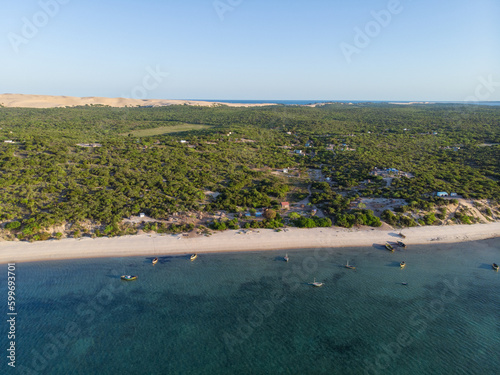 Luftaufnahme von einem Strand in Mosambik, Afrika, mit mehreren kleinen Fischerbooten auf dem Meer vor dem weiten Sandstrand mit Palmen photo