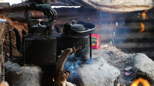 Tea is boiled in two burning aluminum kettles in a clay oven. urbanized everyday scene. Slow-motion video.