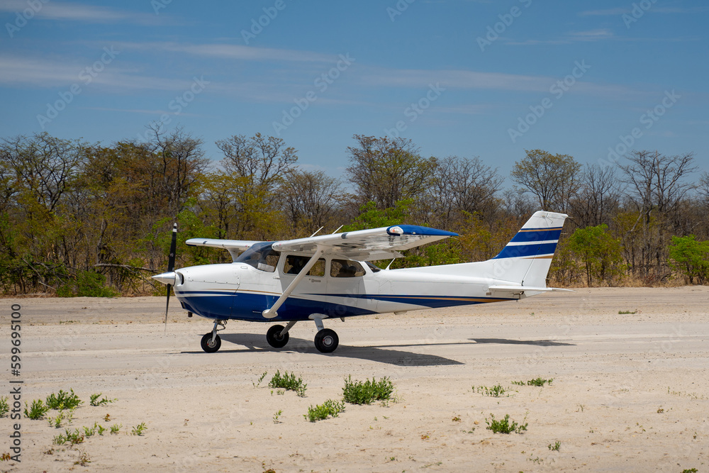 Propellerflugzeug Cessna rollt über eine Schotterpiste / Airstrip im Okavango Delta in Botswana, Afrika Propellerflugzeug Cessna rollt über eine Schotterpiste / Airstrip im Okavango Delta in Botswana, Afrika