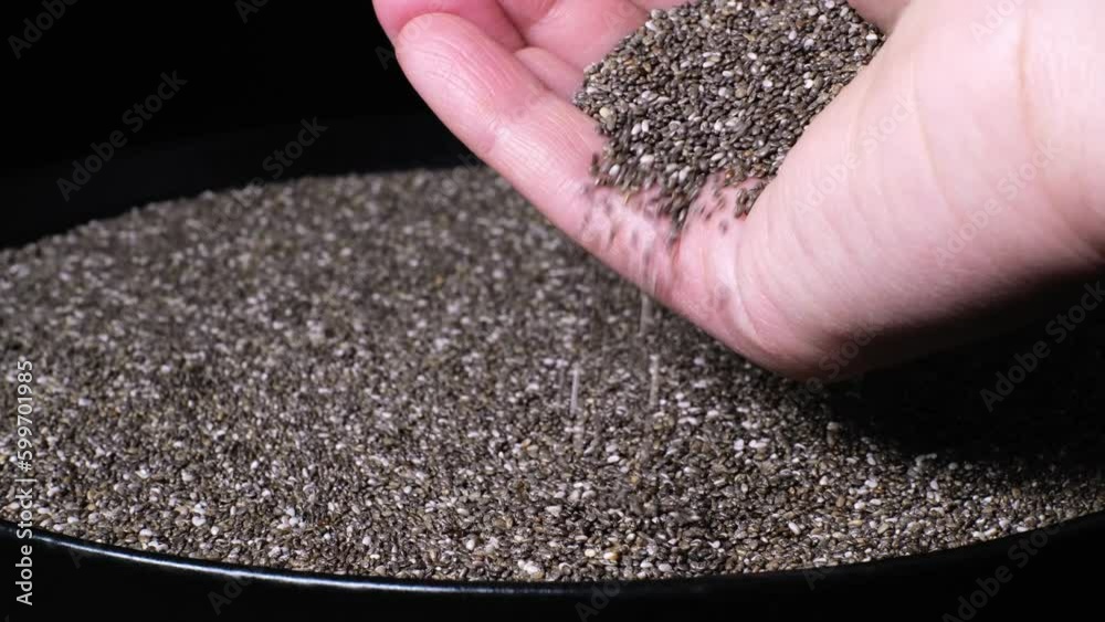 Slow motion of female hand holding beautiful natural dried chia seeds. Close-up of organic black and white Salvia Hispanica seeds falling down. Healthy superfood, rich in Omega 3 fatty acids. 4K Slow motion of female hand holding beautiful natural dried chia seeds. Close-up of organic black and white Salvia Hispanica seeds falling down. Healthy superfood, rich in Omega 3 fatty acids. 4K