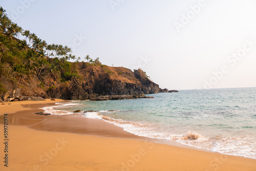 Sea waves at the sea shore of Kakolem beach in Goa  India. Sea waves on the beach  Natural summer background. Tropical beach in India. Palm tree beach with blue sea during the summer time. 