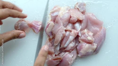 hand cutting raw breast chicken meat on chopping board  photo