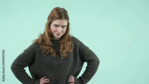 This portrait depicts an emotional girl making gestures. She is a funny Caucasian girl wearing a sweater and laughing while looking at the camera