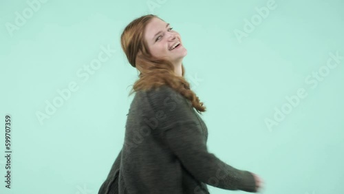 This portrait depicts an emotional girl making gestures. She is a funny Caucasian girl wearing a sweater and laughing while looking at the camera