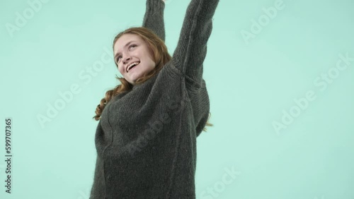 This portrait depicts an emotional girl making gestures. She is a funny Caucasian girl wearing a sweater and laughing while looking at the camera