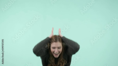 This portrait depicts an emotional girl making gestures. She is a funny Caucasian girl wearing a sweater and laughing while looking at the camera