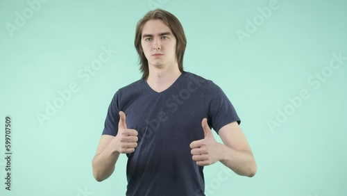 A young man with friendly manners and an emotional facial expression playfully interacts with the camera, dressed in a T-shirt and standing against an isolated background.