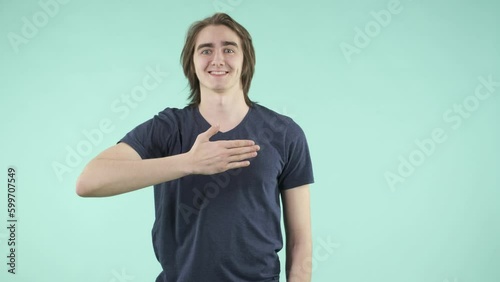 A young man with friendly manners and an emotional facial expression playfully interacts with the camera, dressed in a T-shirt and standing against an isolated background.