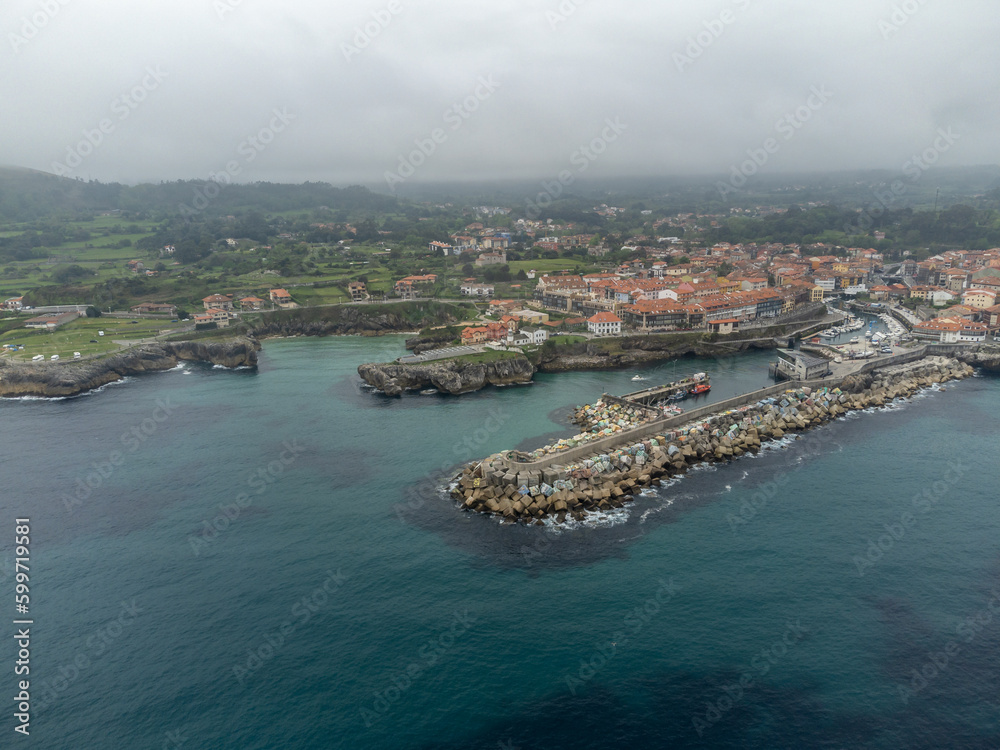Fototapeta premium Aerial view on Playa de Toro and Llanes old harbour, Green coast of Asturias, North Spain with sandy beaches, cliffs, hidden caves, green fields and mountains.