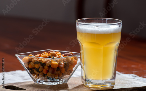 Glass of Belgian white unfiltered beer with notes of coriander and orange peer and different snack nuts