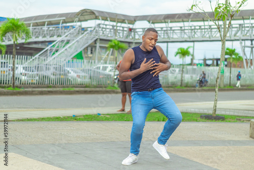 Joven afro baila en el centro de la ciudad con camiseta sin mangas