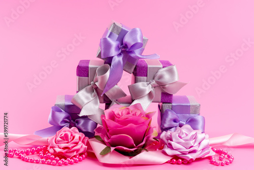 a front view little purple boxes with little designed flowers on the pink background present gift birthday celebration © Kamran