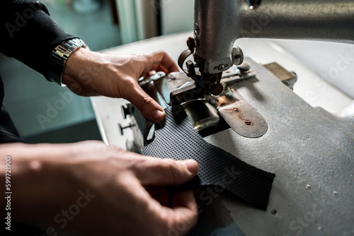 Fotografia, Obraz Mani di tappezziere che lavora un pezzo di stoffa e pelle su una macchina  in un