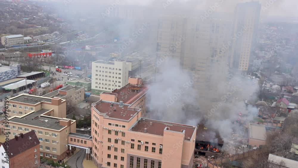 Aerial view of firefighters extinguishing fire in industrial or living area, near high office building after explosion of natural gas Aerial view of firefighters extinguishing fire in industrial or living area, near high office building after explosion of natural gas