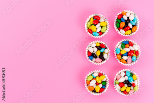 a top view colorful candies inside paper packages on the pink background sugar candy rainbow