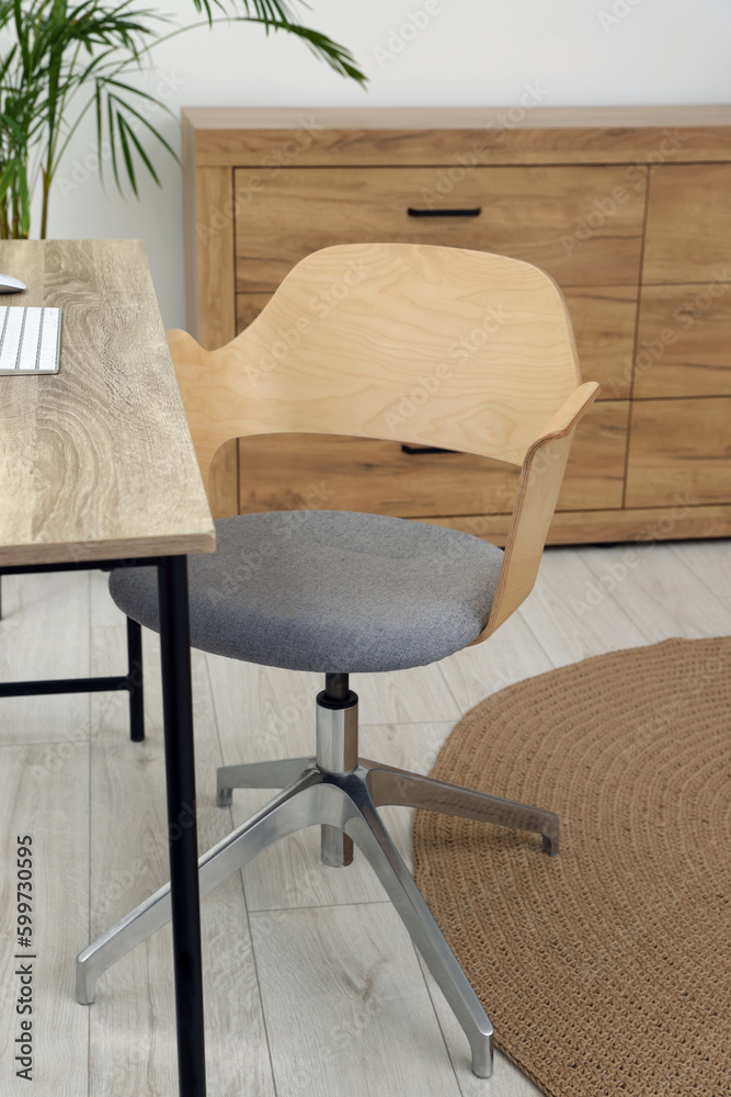 Fototapeta premium Stylish office interior with comfortable chair, desk and houseplant