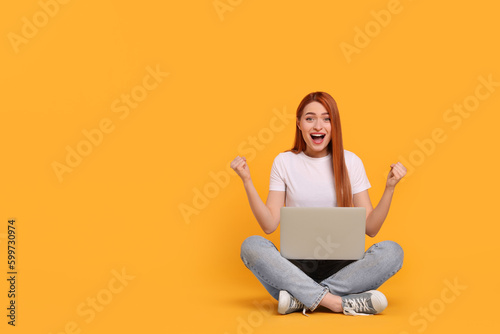 Happy young woman with laptop on yellow background, space for text © New Africa