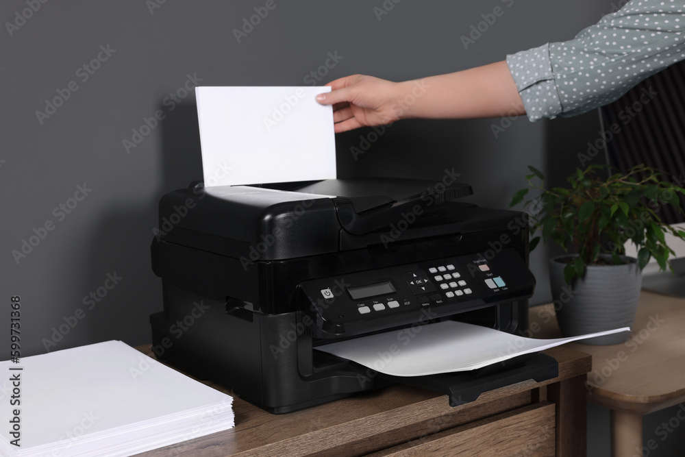 Woman using modern printer at wooden desk in home, closeup